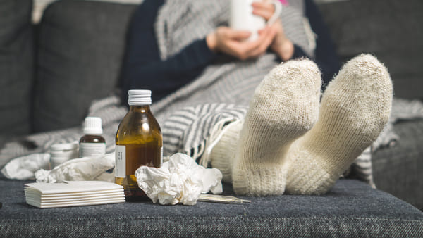 A person sitting on the sofa under blanket not feeling well