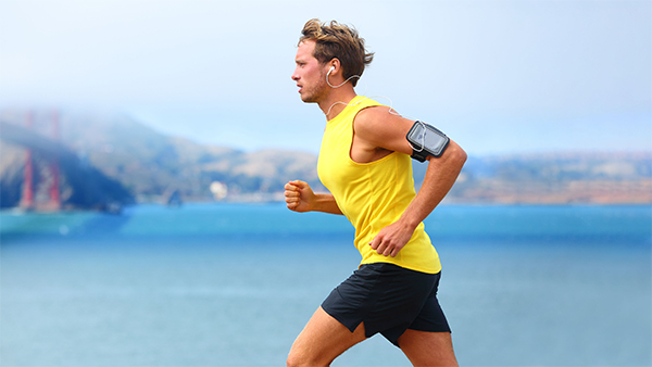 Man in yellow tank top running near lake