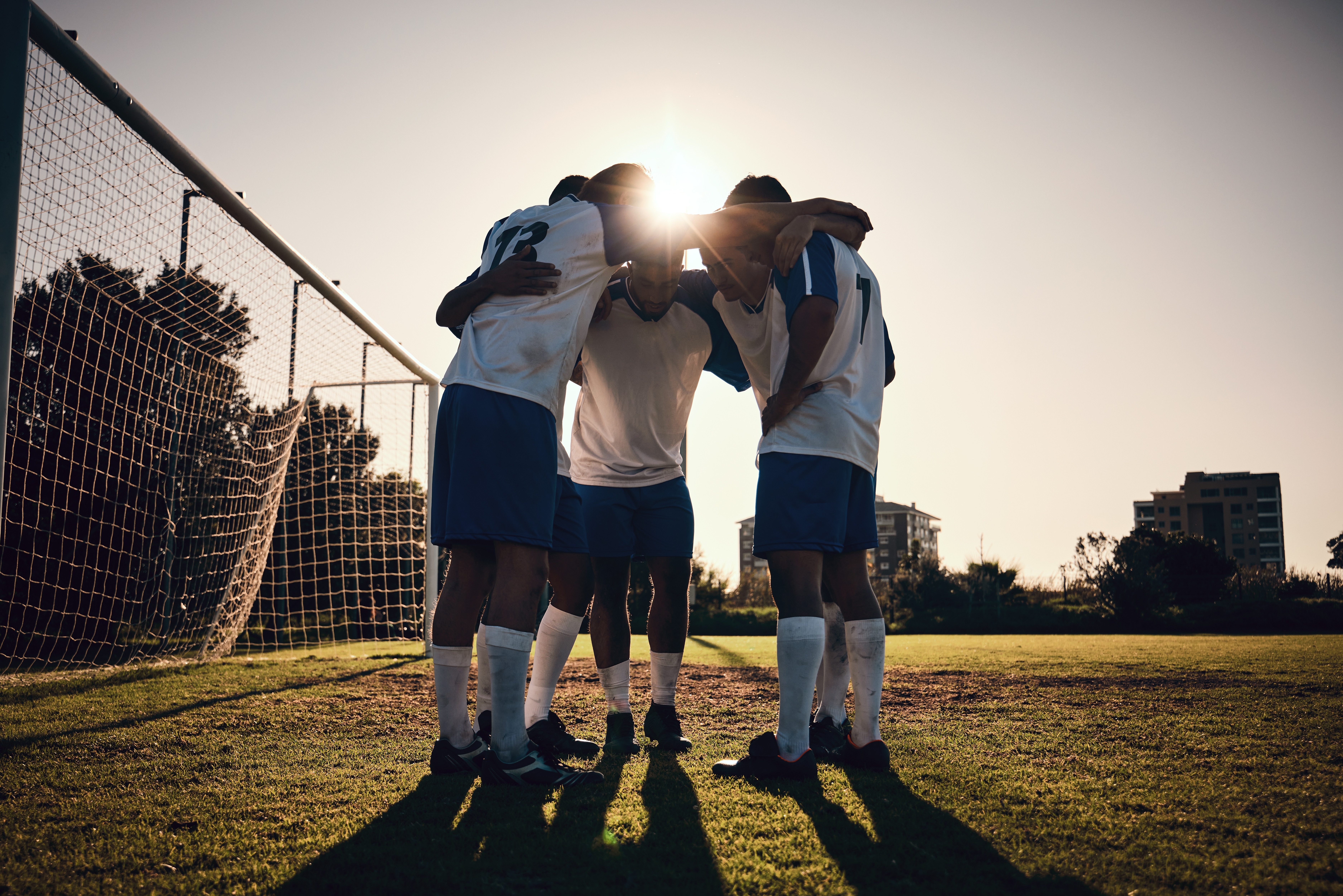 Soccer team in a huddle near a goal