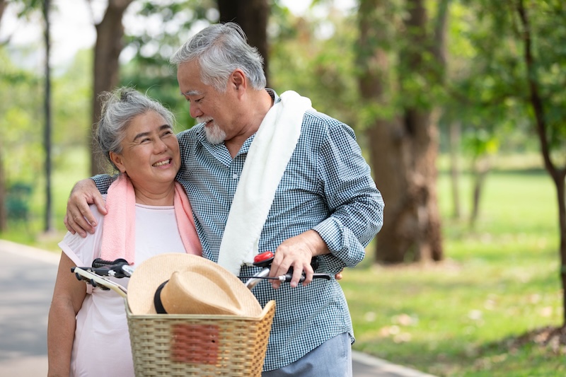 Senior couple embracing and holding hands together in the
park.